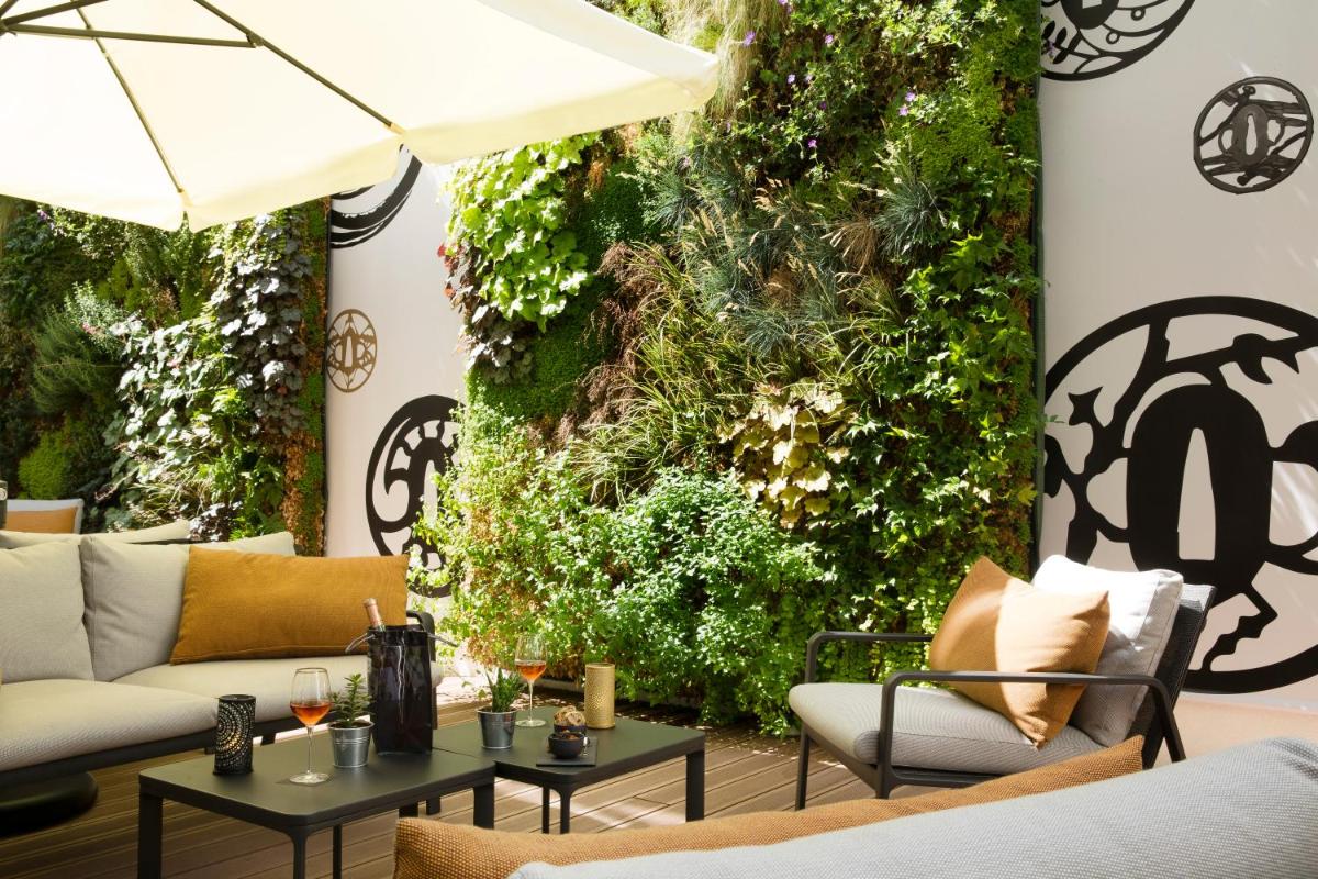 un patio avec un mur végétal aménagé avec des canapés et des tables dans l'établissement Le Tsuba Hotel, à Paris