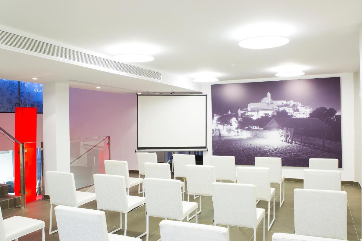 Una habitación con sillas blancas y una pantalla de proyección. en Migjorn Ibiza Suites & Spa, en Playa d'en Bossa 121 fotos más
