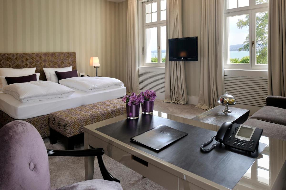 ein Hotelzimmer mit einem Schreibtisch und einem Bett mit einem Telefon in der Unterkunft RIVA - Das Hotel am Bodensee in Konstanz