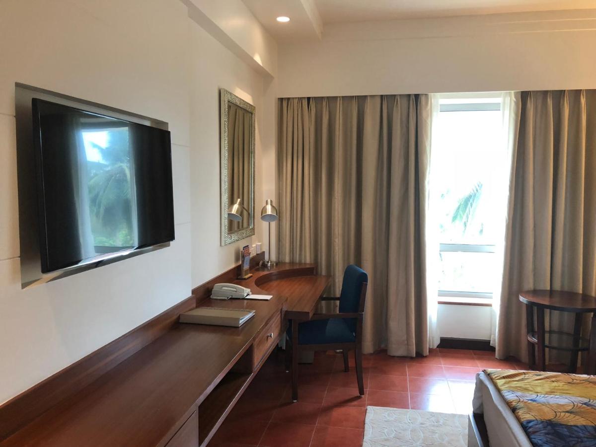 a hotel room with a desk and a television on the wall at Fortune Miramar, Goa - Member ITC Hotels' Group in Panaji a hotel room with a desk and a television on the wall at Fortune Miramar, Goa - Member ITC Hotels' Group in Panaji