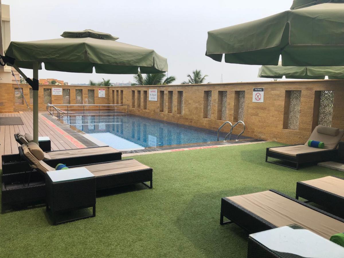 a pool with chairs and an umbrella next to a building at Fortune Miramar, Goa - Member ITC Hotels' Group in Panaji a pool with chairs and an umbrella next to a building at Fortune Miramar, Goa - Member ITC Hotels' Group in Panaji