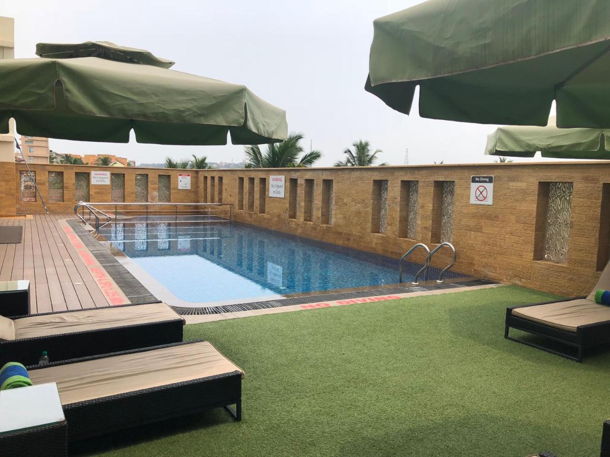 a swimming pool with benches and an umbrella at Fortune Miramar, Goa - Member ITC Hotels' Group in Panaji a swimming pool with benches and an umbrella at Fortune Miramar, Goa - Member ITC Hotels' Group in Panaji