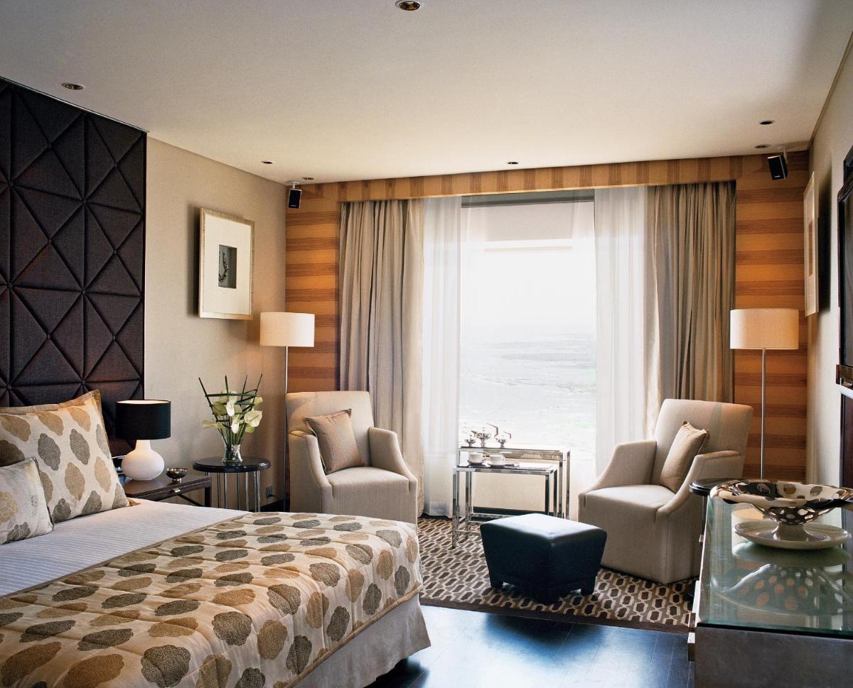 a bedroom with a bed and two chairs and a window at Taj Lands End in Mumbai a bedroom with a bed and two chairs and a window at Taj Lands End in Mumbai