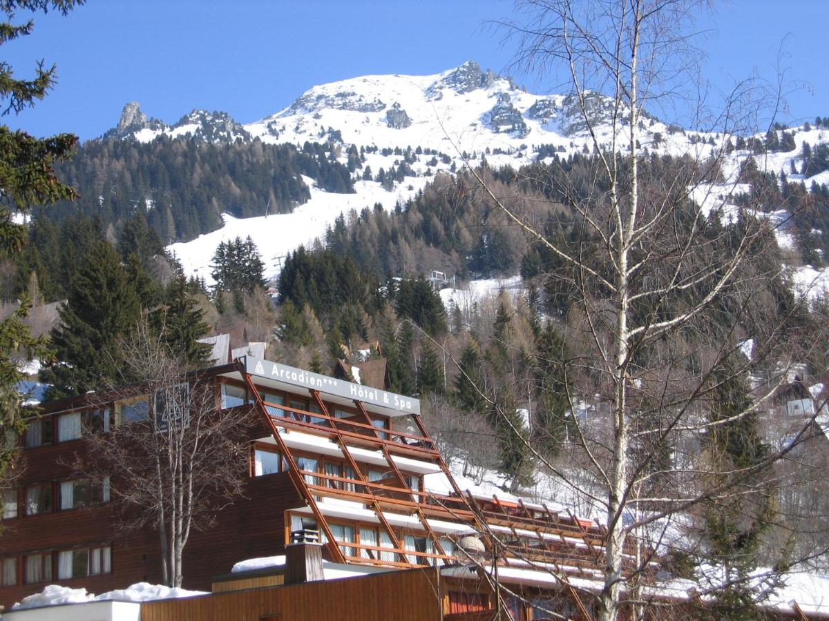un bâtiment avec une montagne enneigée en arrière-plan dans l'établissement Hôtel Arcadien, à Arc 1600