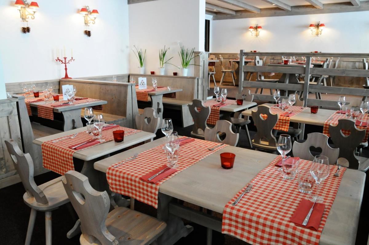un restaurant avec tables et chaises et nappes rouges et blanches dans l'établissement Hôtel Arcadien, à Arc 1600 25 autres photos