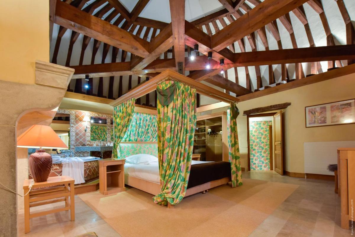 une chambre avec deux lits et un plafond à poutres apparentes dans l'établissement Hôtel Golf Château de Chailly, à Chailly-sur-Armançon
