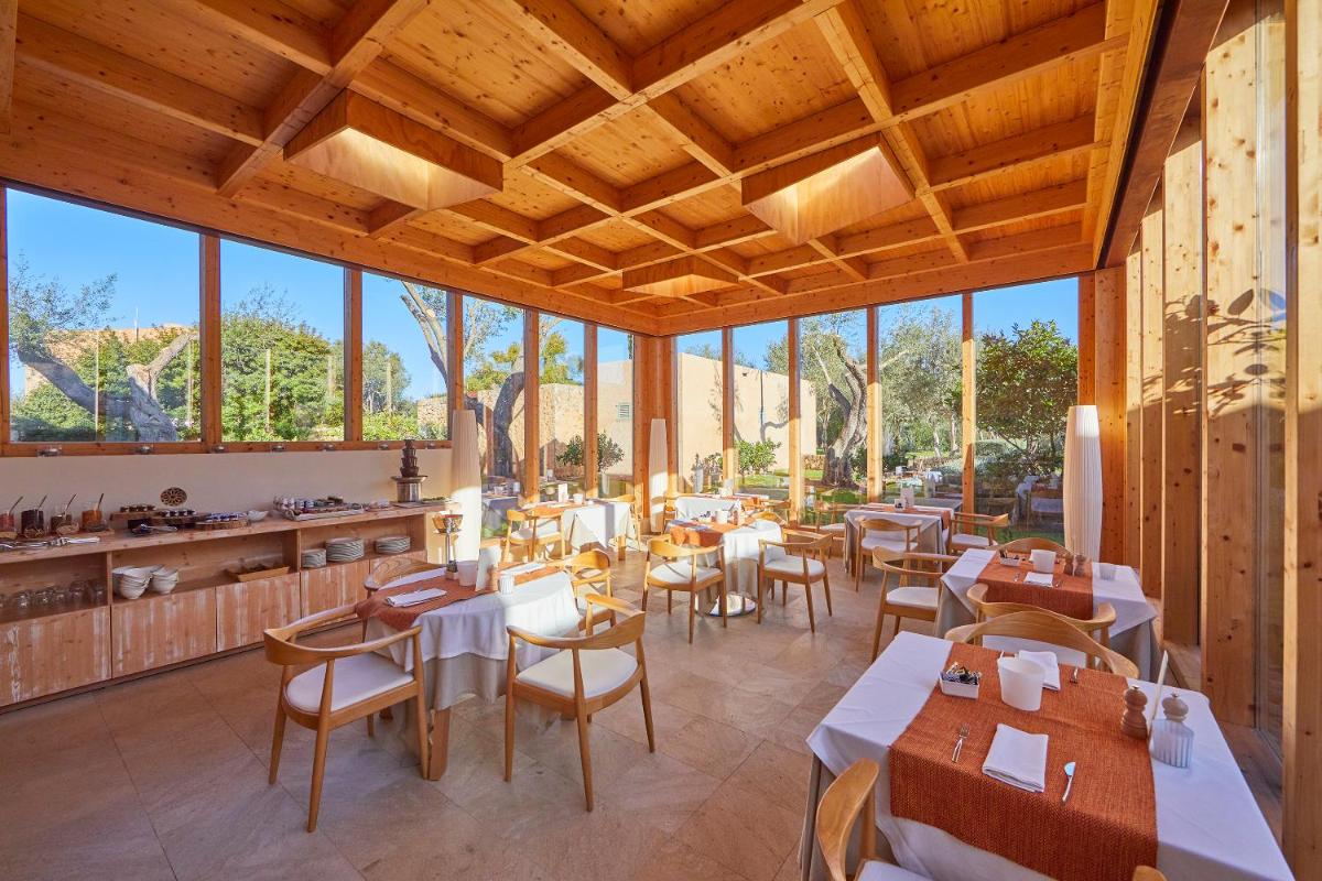 Un restaurante con mesas, sillas y ventanas. en Son Penya Adults Only Petit Hotel & Spa, en Sant Llorenç des Cardassar