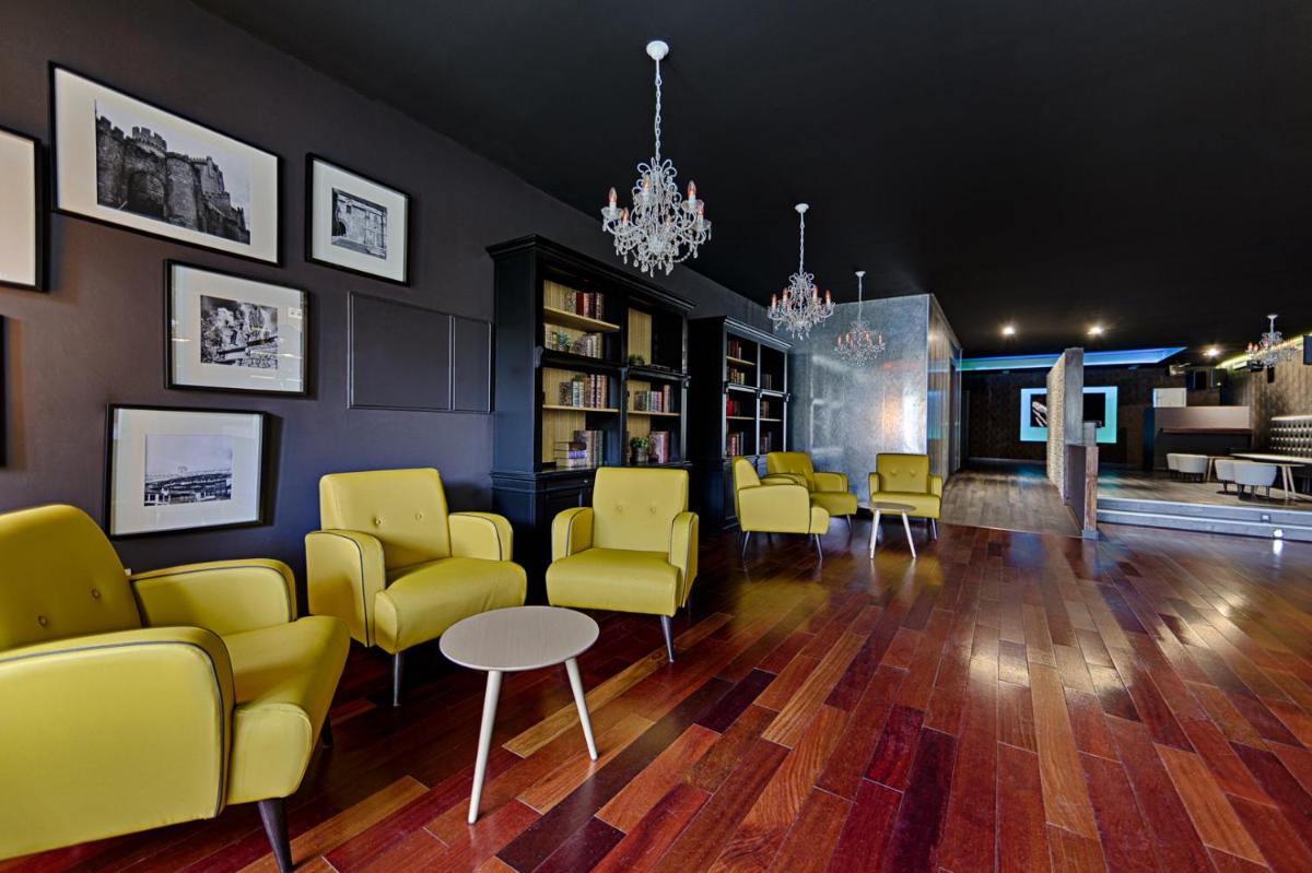 Una sala de espera con sillas amarillas y una mesa. en AZZ Peñafiel Las Claras Hotel & Spa, en Peñafiel