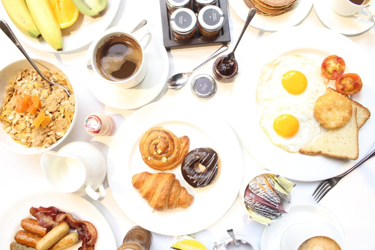 a table with plates of breakfast foods on it at Roseate House New Delhi in New Delhi a table with plates of breakfast foods on it at Roseate House New Delhi in New Delhi