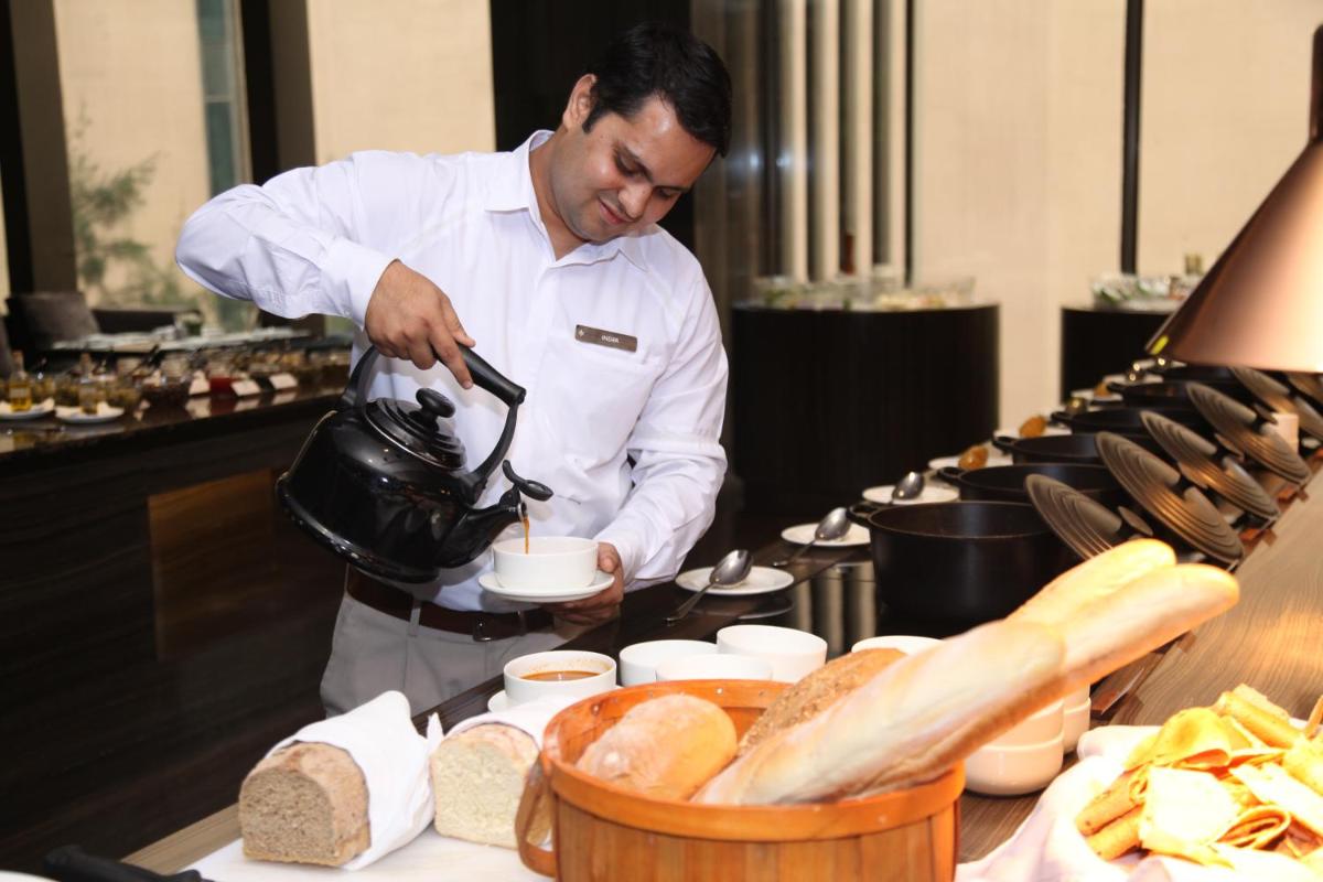 a chef preparing food in a restaurant kitchen at Roseate House New Delhi in New Delhi a chef preparing food in a restaurant kitchen at Roseate House New Delhi in New Delhi