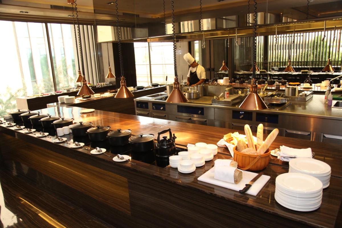 a restaurant kitchen with a counter with plates and food at Roseate House New Delhi in New Delhi a restaurant kitchen with a counter with plates and food at Roseate House New Delhi in New Delhi