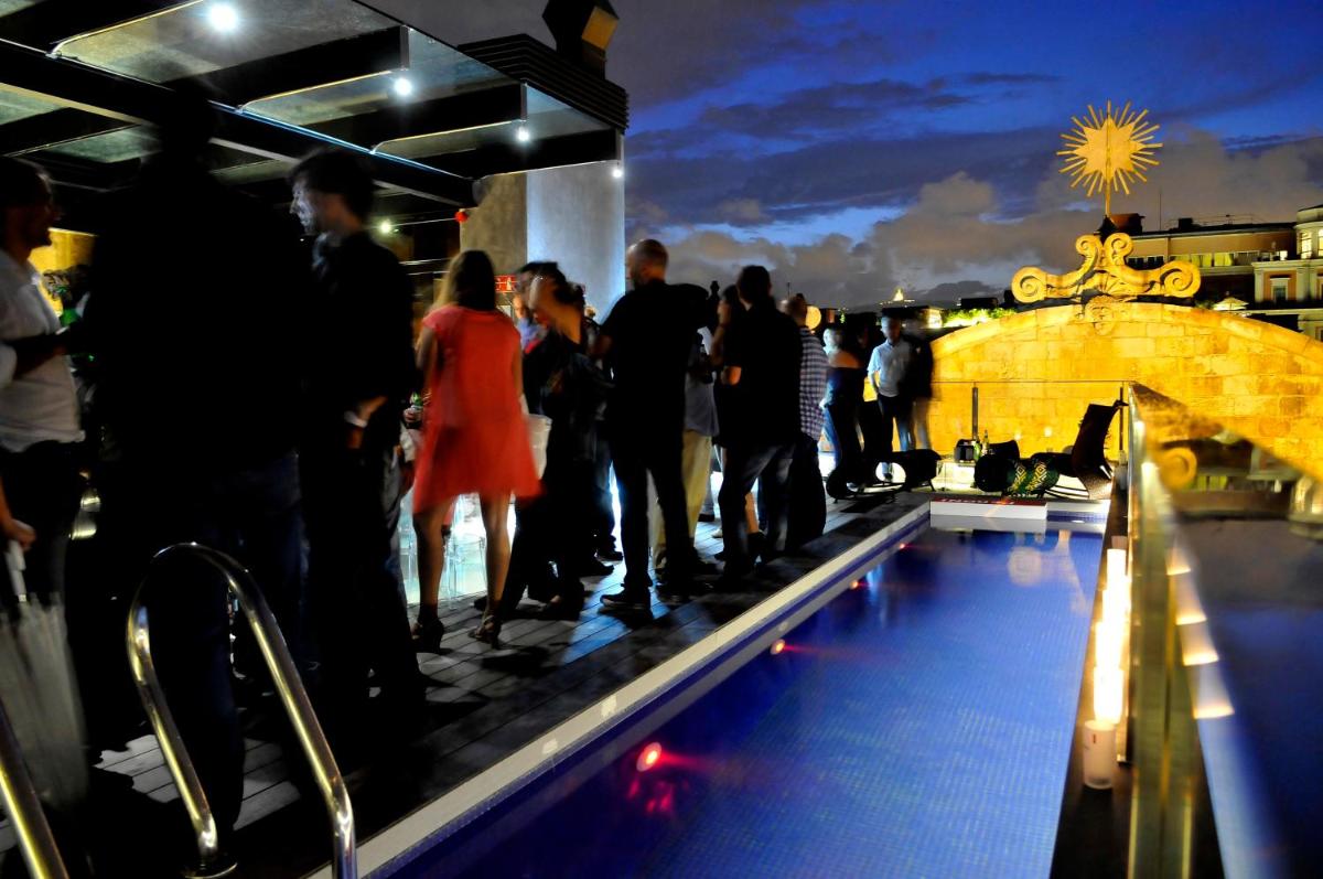 un grupo de personas de pie alrededor de una piscina por la noche en Hotel Bagués, a Small Luxury Hotel of the World, en Barcelona