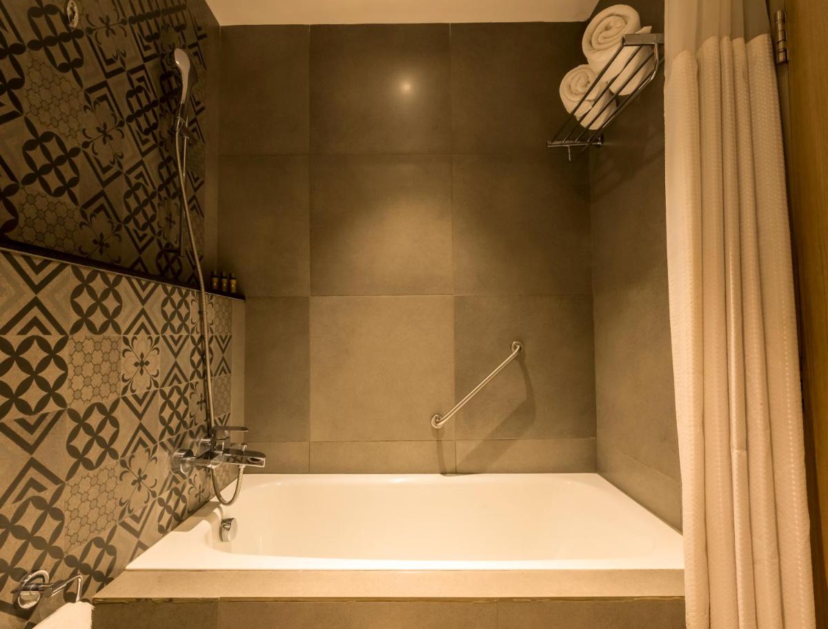 a bath tub in a bathroom with a shower curtain at Grand Mercure Mysore - An Accor Brand in Mysore