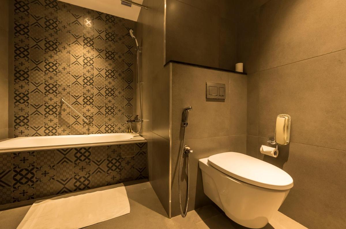 a bathroom with a toilet and a phone on the wall at Grand Mercure Mysore - An Accor Brand in Mysore