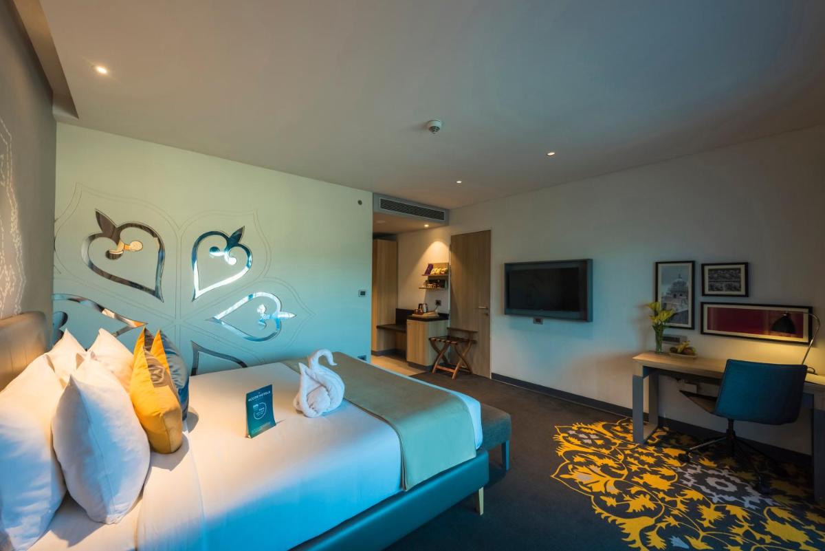 a hotel room with a bed and a desk at Grand Mercure Mysore - An Accor Brand in Mysore