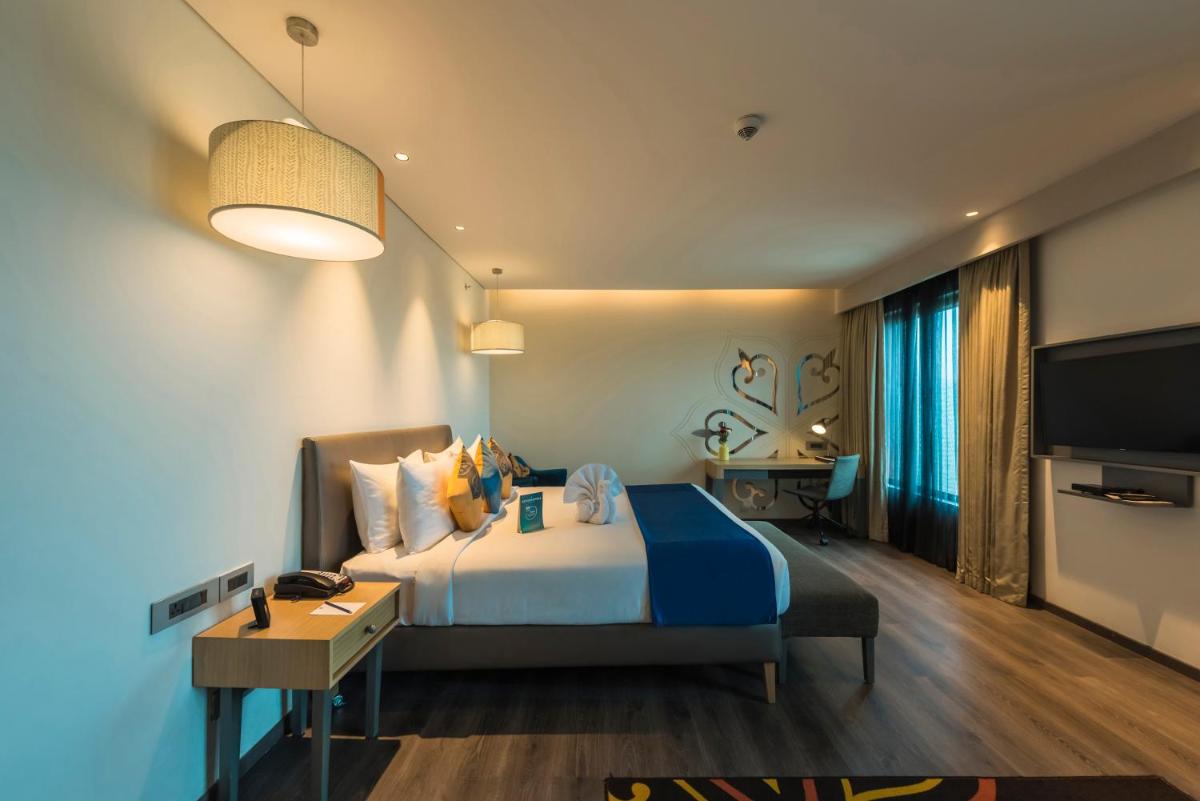 a hotel room with a bed and a television at Grand Mercure Mysore - An Accor Brand in Mysore