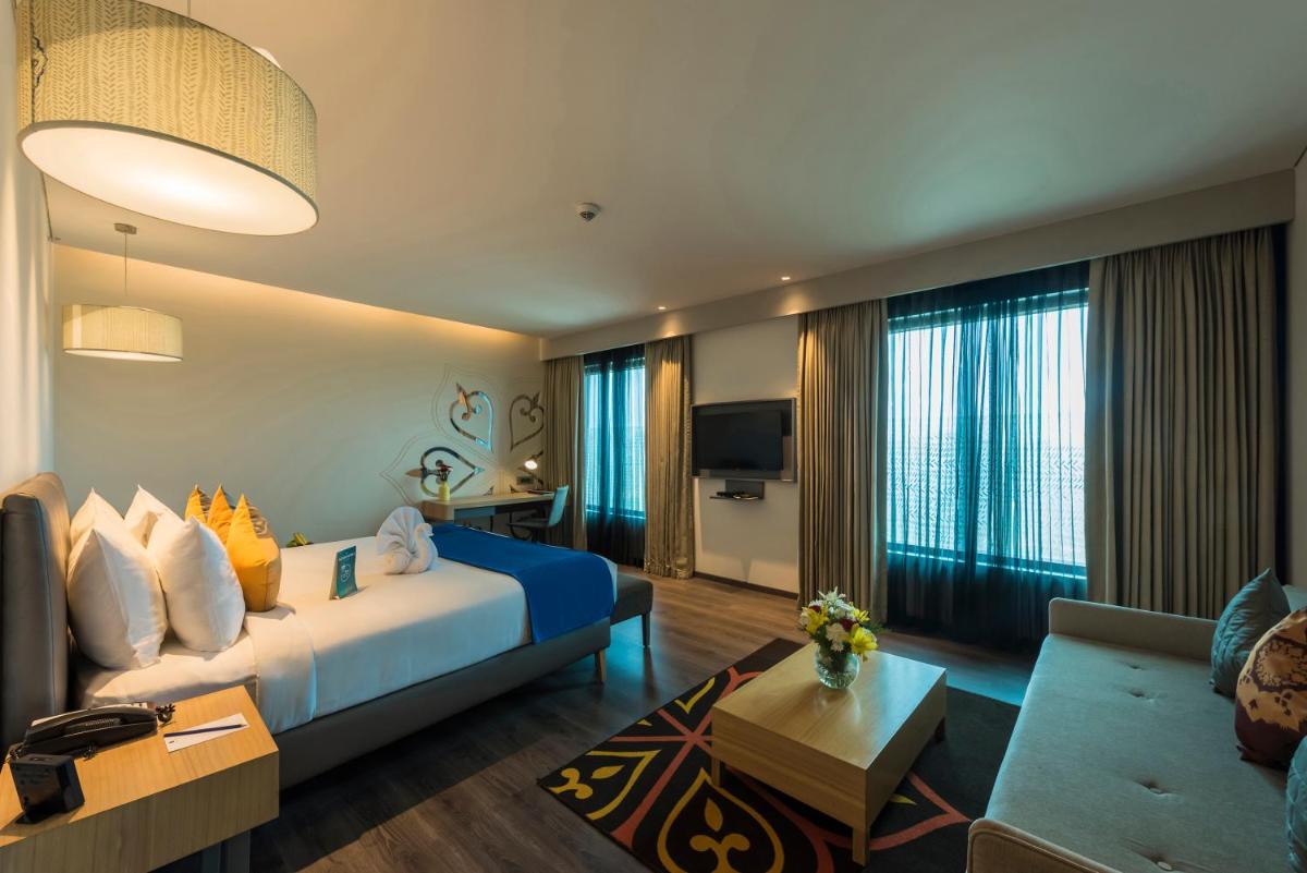 a hotel room with a blue bed and a couch at Grand Mercure Mysore - An Accor Brand in Mysore