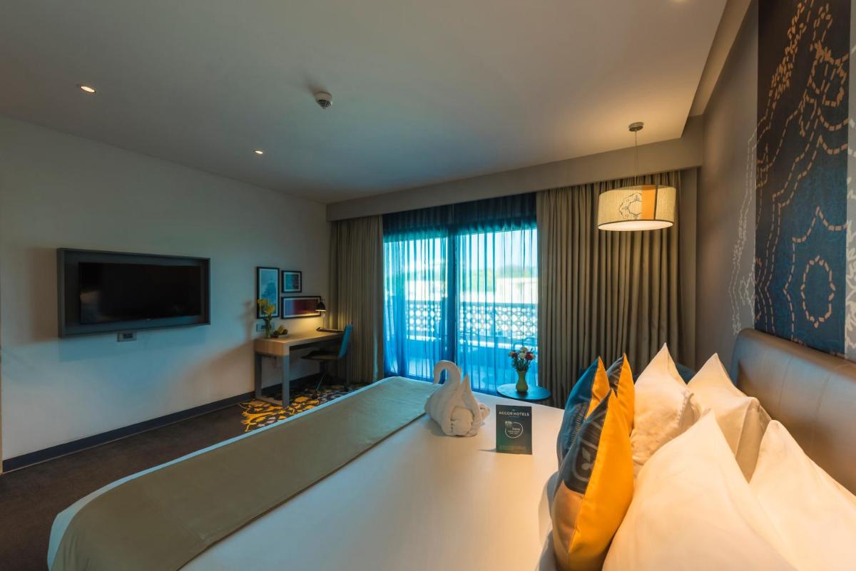 a hotel room with a bed and a television at Grand Mercure Mysore - An Accor Brand in Mysore