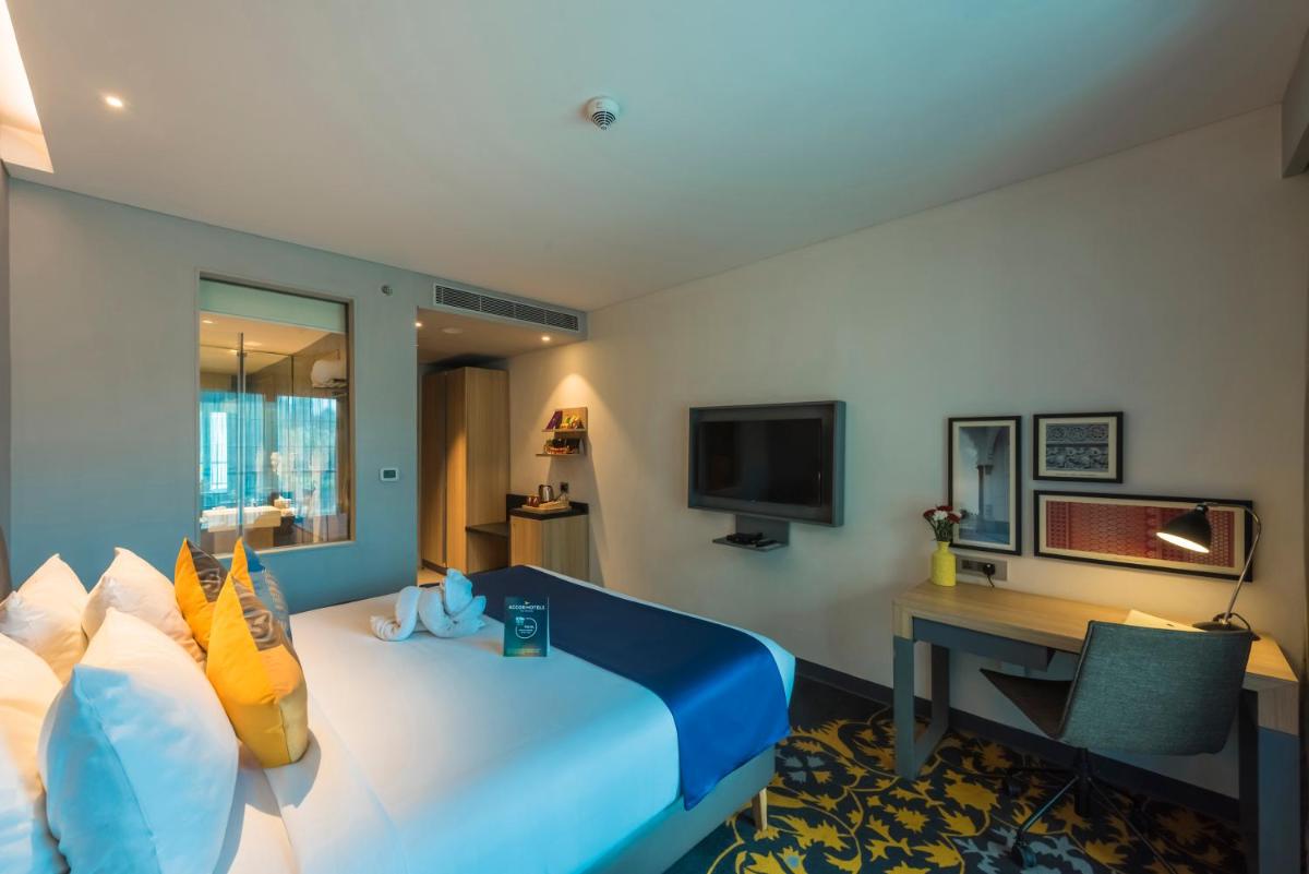 a hotel room with a large bed with a desk at Grand Mercure Mysore - An Accor Brand in Mysore