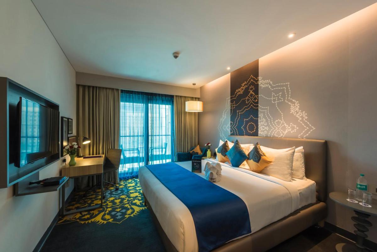 a hotel room with a large bed and a television at Grand Mercure Mysore - An Accor Brand in Mysore