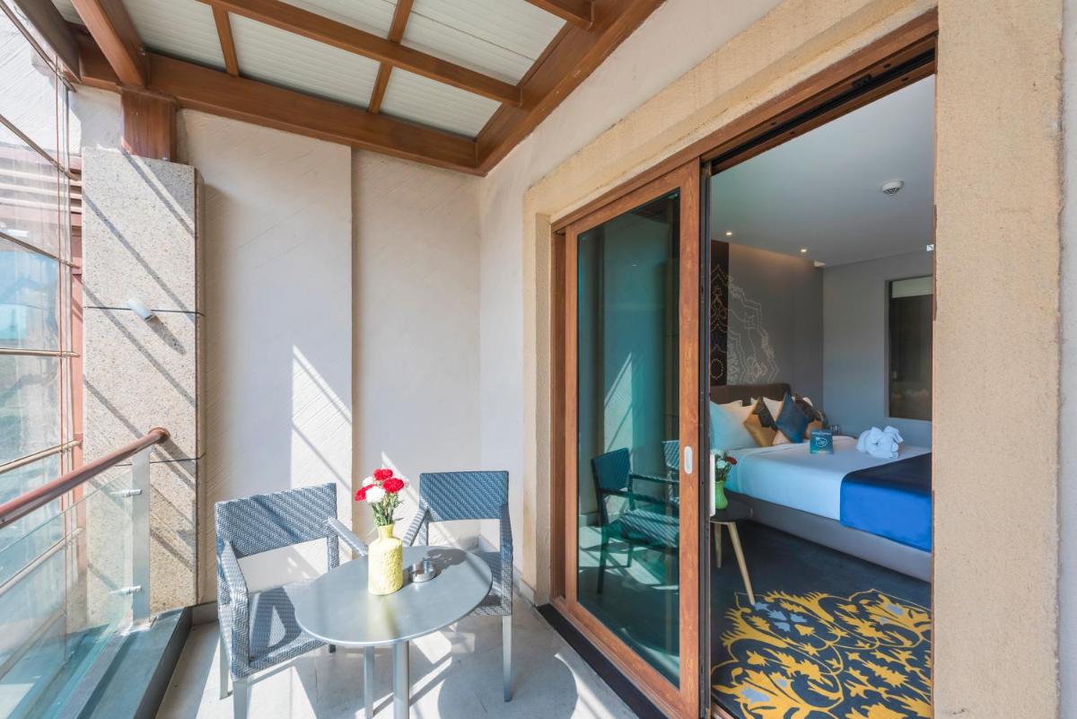 a room with a balcony with a bed and a table at Grand Mercure Mysore - An Accor Brand in Mysore