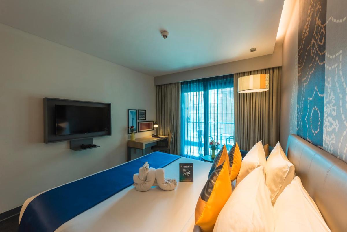 a hotel room with a bed and a flat screen tv at Grand Mercure Mysore - An Accor Brand in Mysore