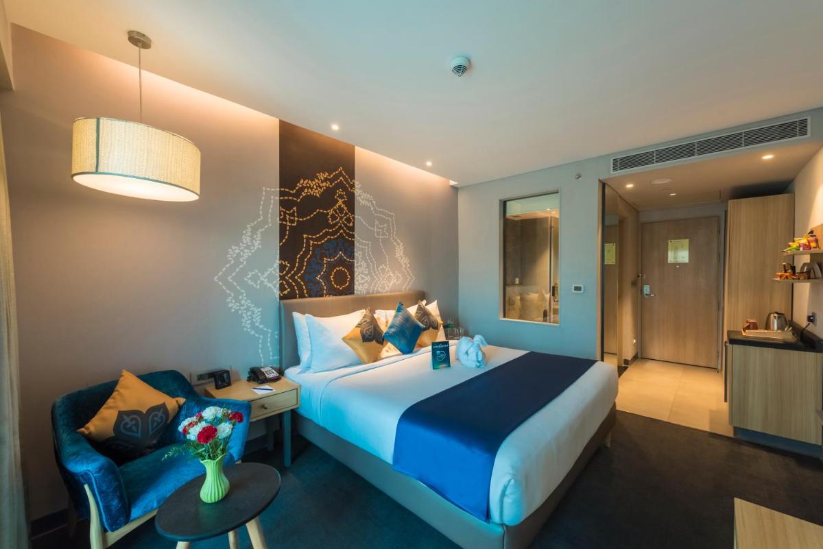a hotel room with a large bed and a chair at Grand Mercure Mysore - An Accor Brand in Mysore