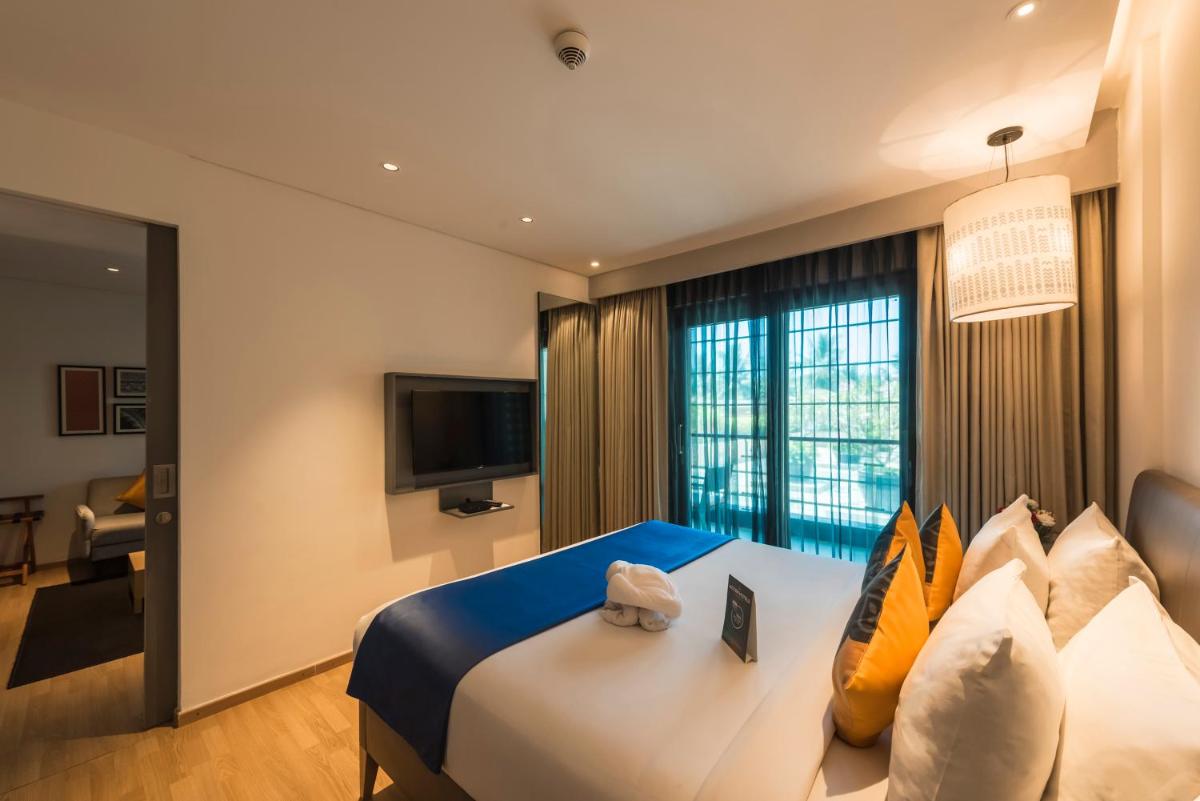 a hotel room with a bed and a television at Grand Mercure Mysore - An Accor Brand in Mysore