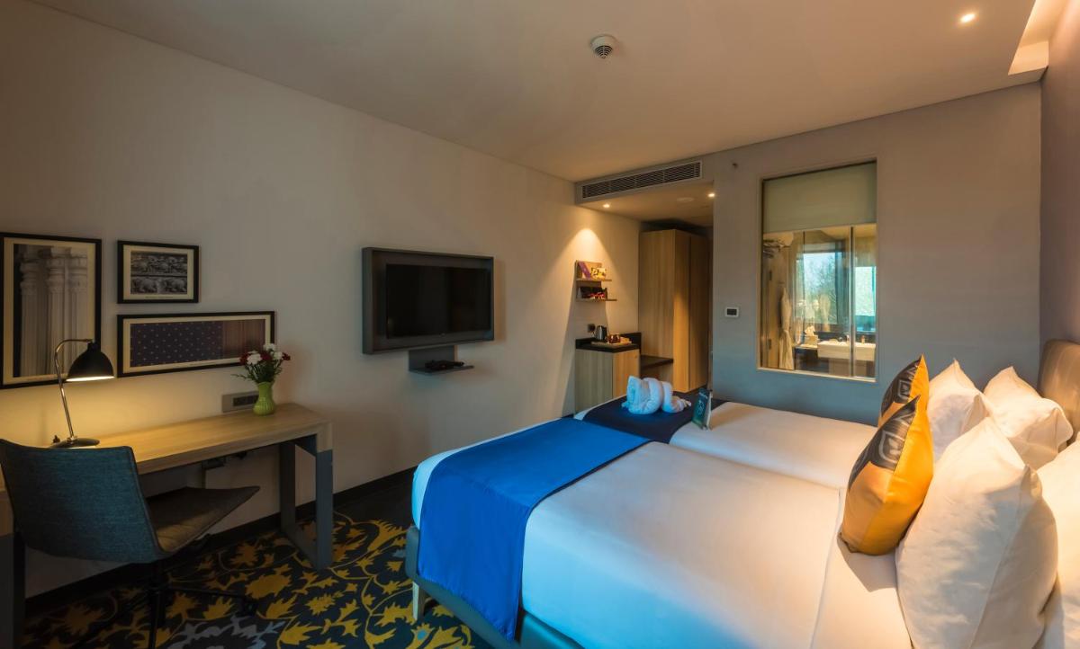 a hotel room with a bed and a desk and a television at Grand Mercure Mysore - An Accor Brand in Mysore