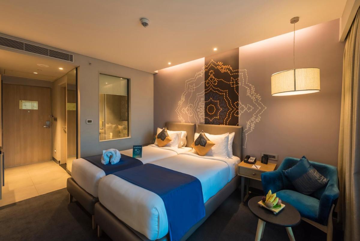 a hotel room with a large bed and a chair at Grand Mercure Mysore - An Accor Brand in Mysore
