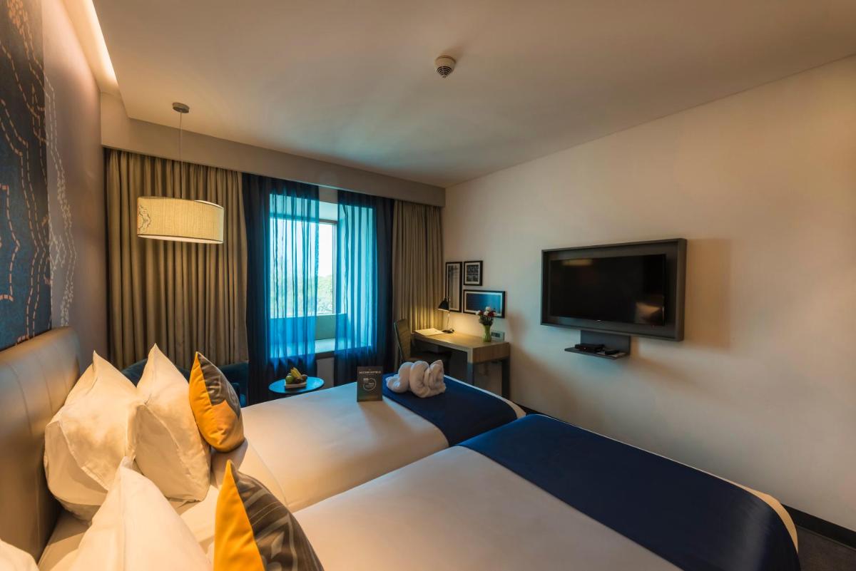 a hotel room with a bed and a flat screen tv at Grand Mercure Mysore - An Accor Brand in Mysore