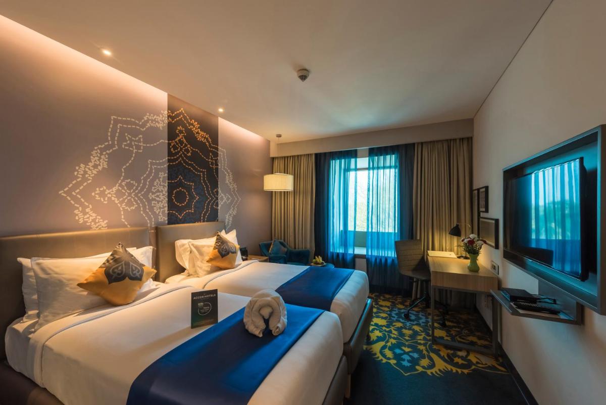 a hotel room with two beds and a desk at Grand Mercure Mysore - An Accor Brand in Mysore