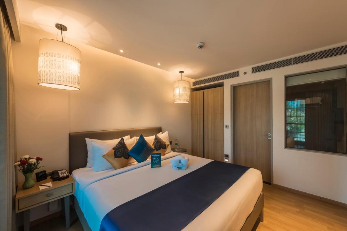 a bedroom with a large bed and two lights at Grand Mercure Mysore - An Accor Brand in Mysore