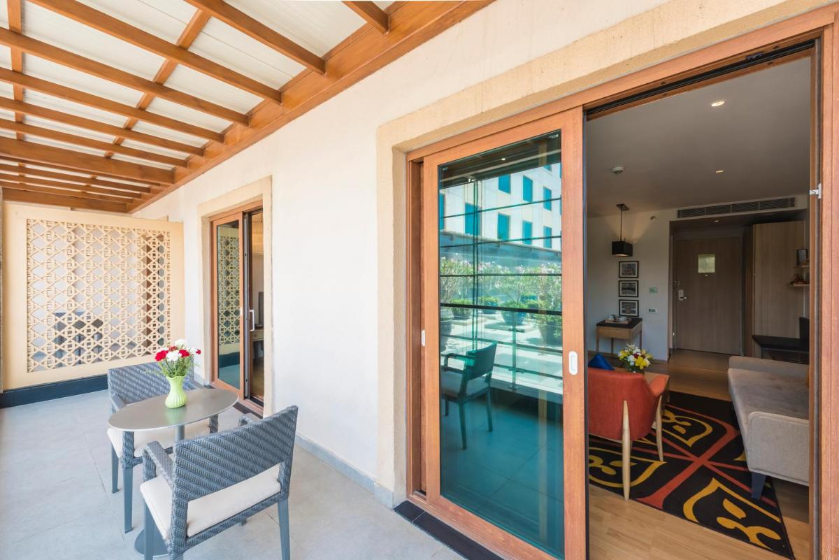 a room with a table and chairs and a glass door at Grand Mercure Mysore - An Accor Brand in Mysore