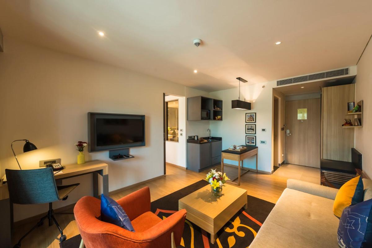 a living room with orange chairs and a television at Grand Mercure Mysore - An Accor Brand in Mysore