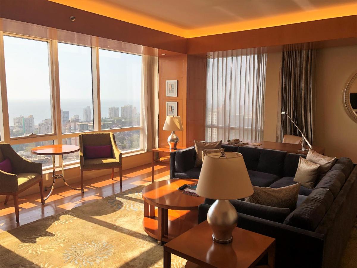a living room with a couch and a large window at Four Seasons Hotel Mumbai in Mumbai
