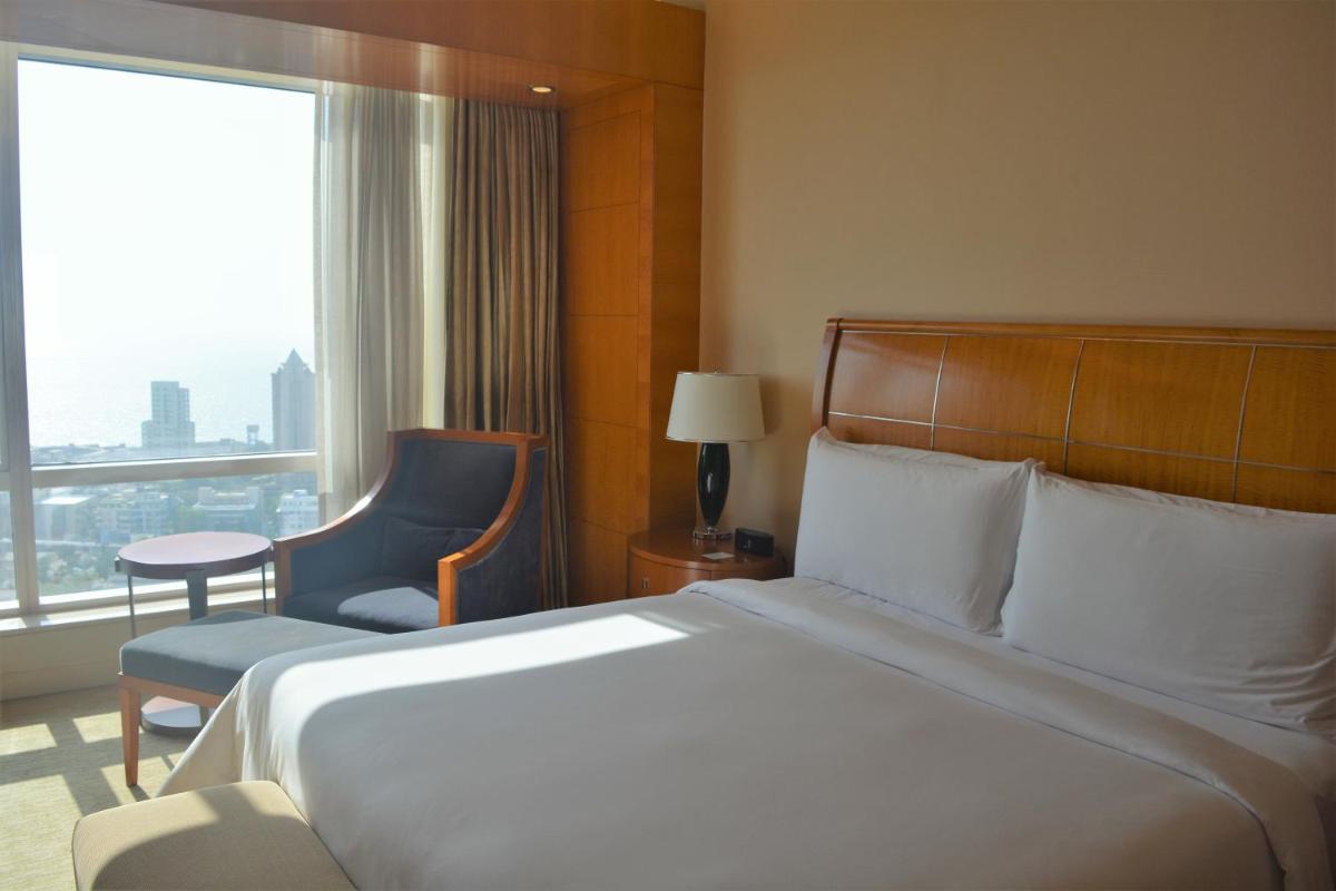 a hotel room with a bed and a chair and a window at Four Seasons Hotel Mumbai in Mumbai
