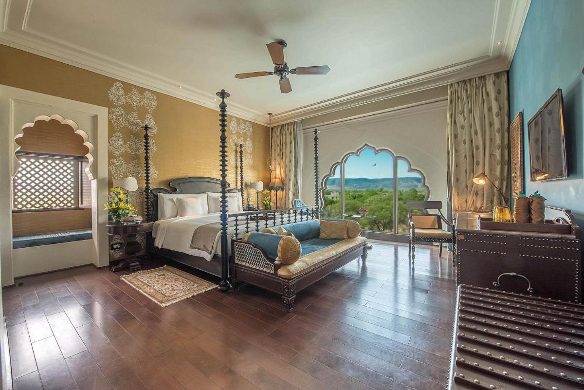 a bedroom with a bed and a couch and a ceiling fan at Fairmont Jaipur in Jaipur