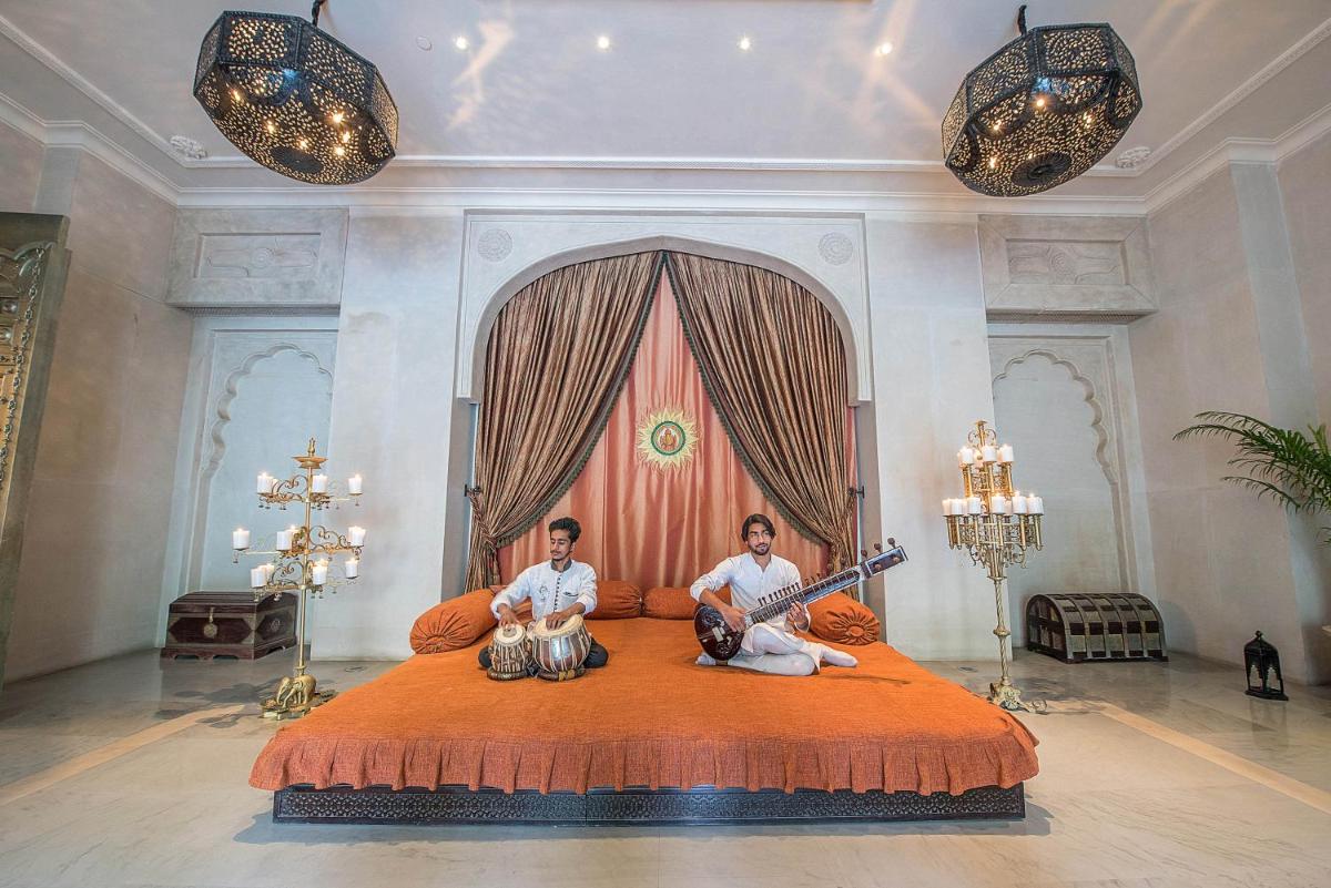 two men sitting on a bed in a room at Fairmont Jaipur in Jaipur