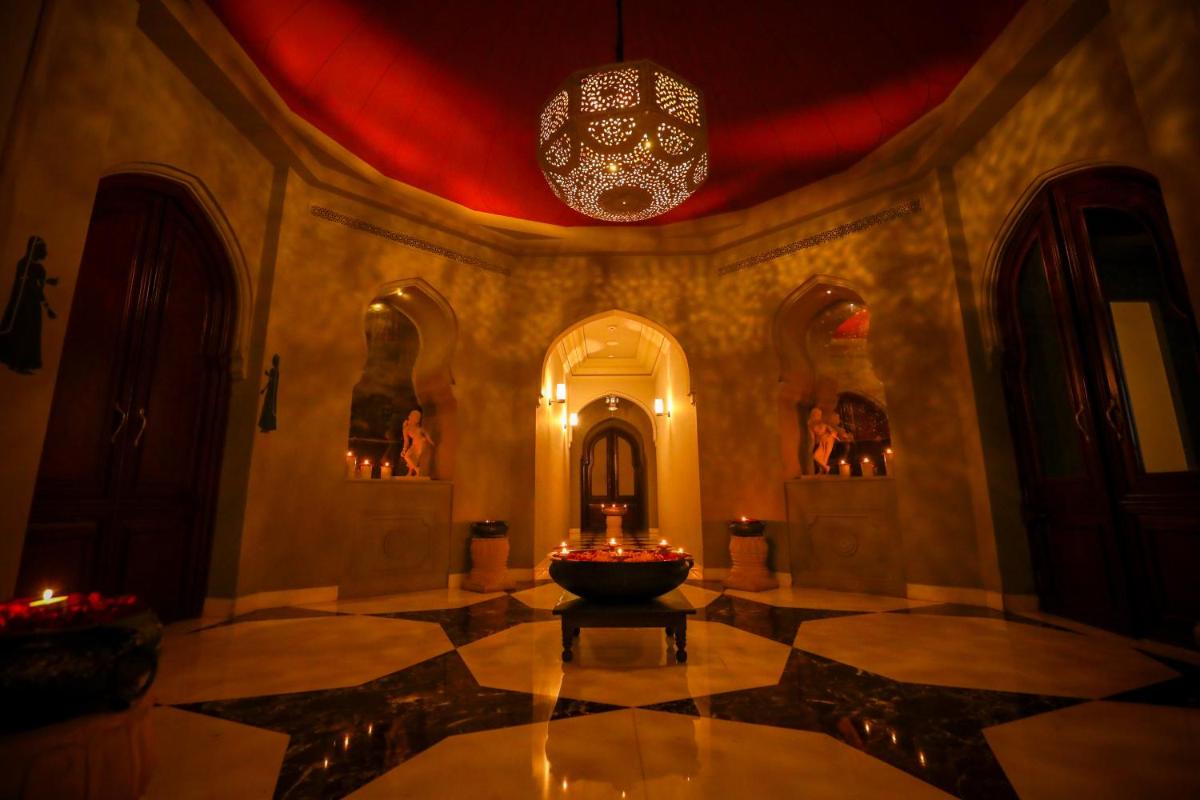 a room with a chandelier and a fountain in the middle of a building at Fairmont Jaipur in Jaipur