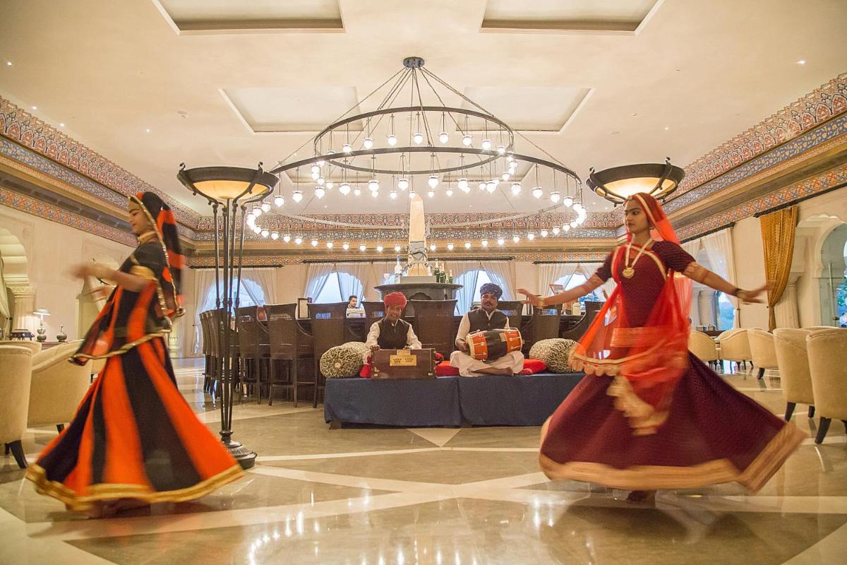 two women in colorful dresses dancing in a room at Fairmont Jaipur in Jaipur