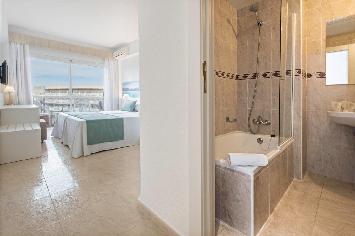 Un baño con bañera y un dormitorio con cama. en azuLine Hotel Bahamas y Bahamas II, en El Arenal