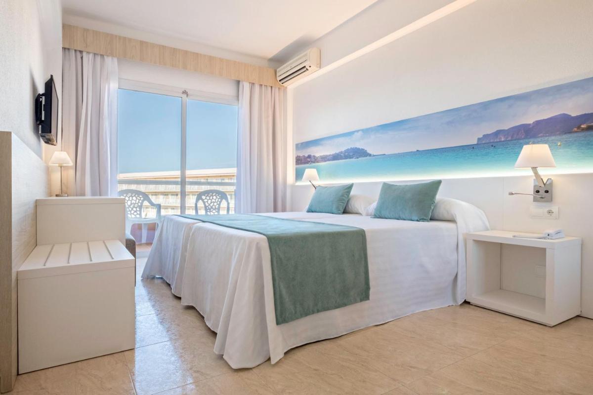 Un dormitorio con una cama y una ventana grande. en azuLine Hotel Bahamas y Bahamas II, en El Arenal