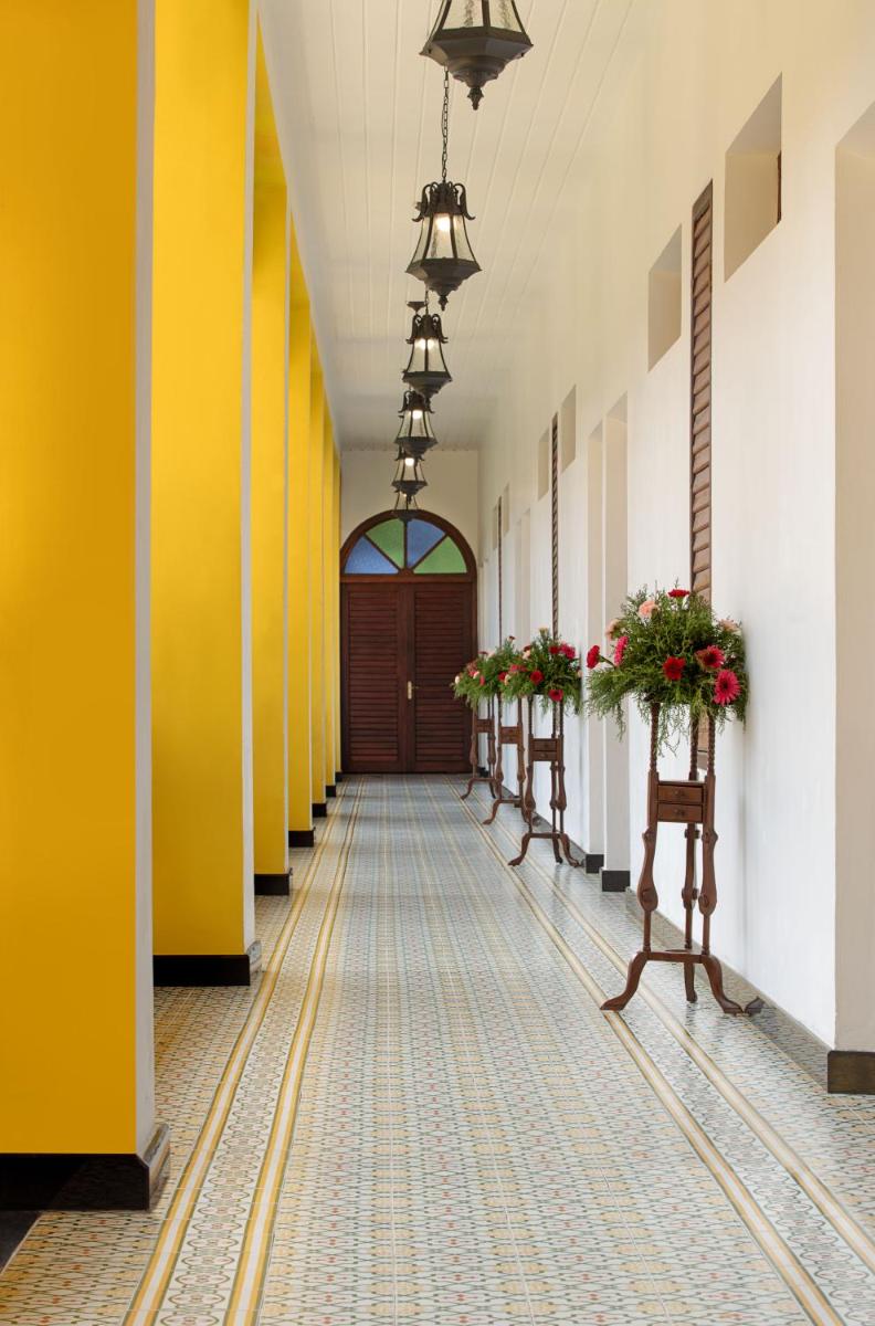 a hallway with yellow and white walls and a door at Forte Kochi in Cochin