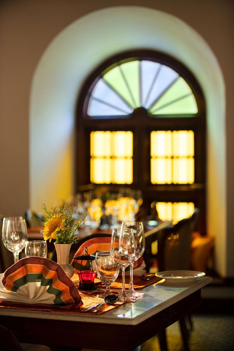 a table with wine glasses on it with a window at Forte Kochi in Cochin