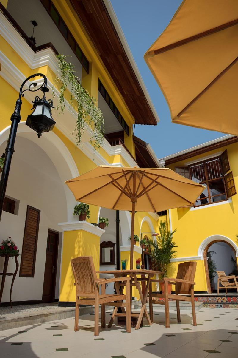 a patio with tables and umbrellas in front of a building at Forte Kochi in Cochin