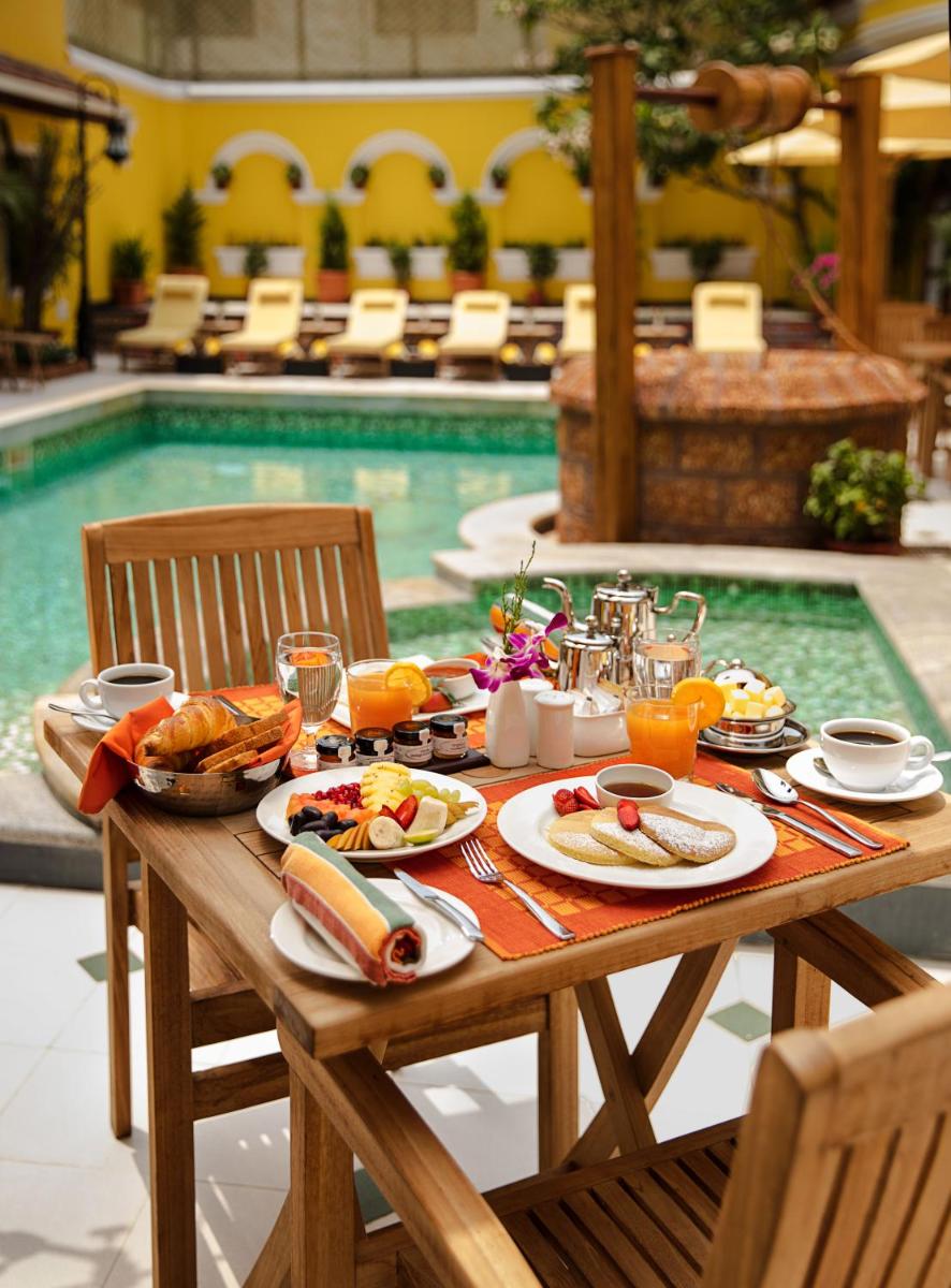 a table with food on it next to a swimming pool at Forte Kochi in Cochin
