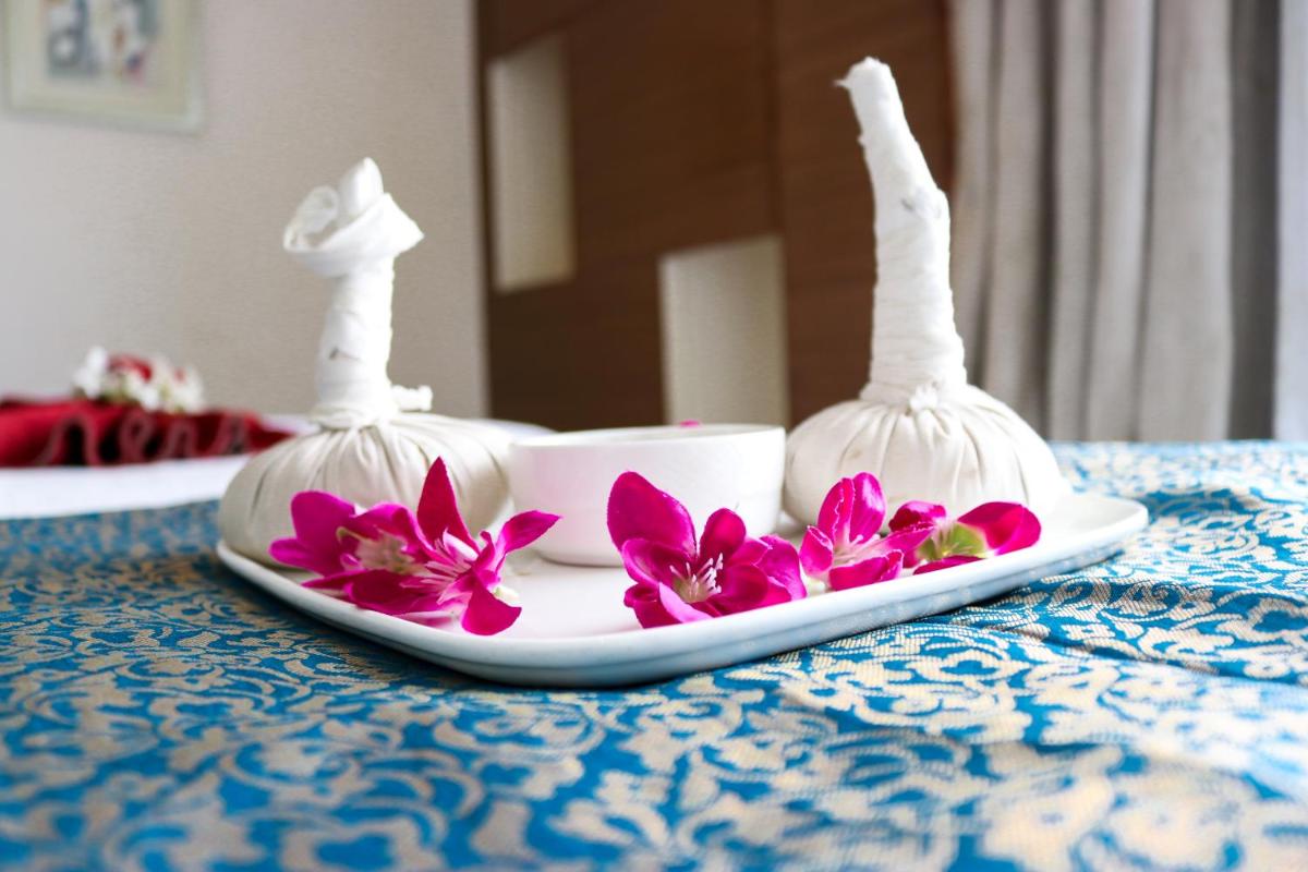 a plate with two white vases and flowers on a table at Radisson Blu Hotel, Greater Noida in Greater Noida