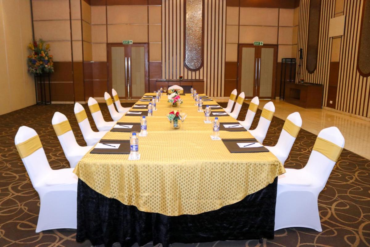 a long table with white chairs and a yellow table cloth at Radisson Blu Hotel, Greater Noida in Greater Noida