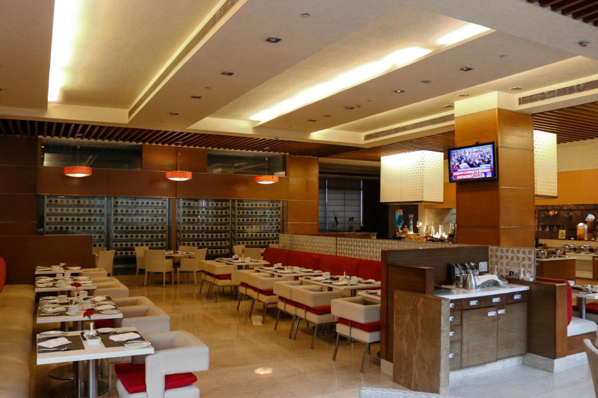 a restaurant with tables and chairs and a television at Radisson Blu Hotel, Greater Noida in Greater Noida